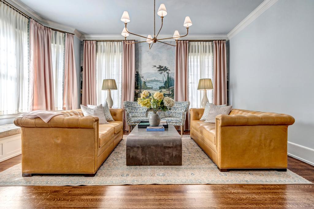 Two facing tufted leather sofas floated off the walls on a pale rug, with a patterned settee between them