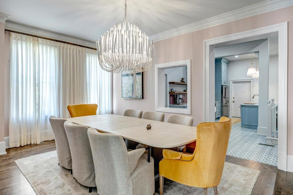 Pale oak dining table with gray channel-back chairs and gold velvet host chairs