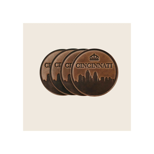 Set of four round brown leather coasters embossed with Cincinnati skyline and crown motif, stacked and fanned