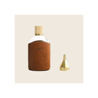 Glass flask in tan leather sleeve with brass knurled cap and small brass funnel accessory