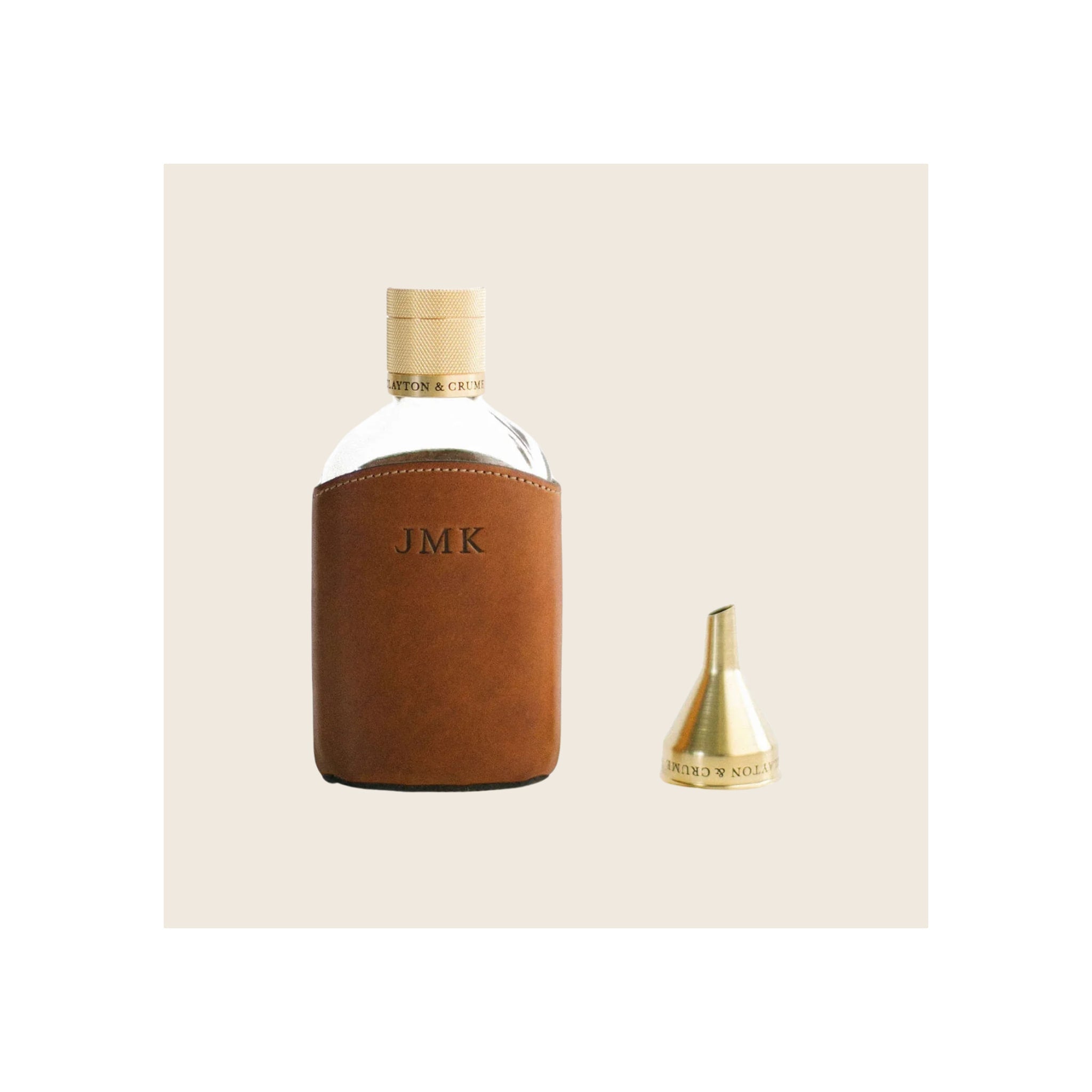 Glass flask in tan leather sleeve with brass knurled cap and small brass funnel accessory