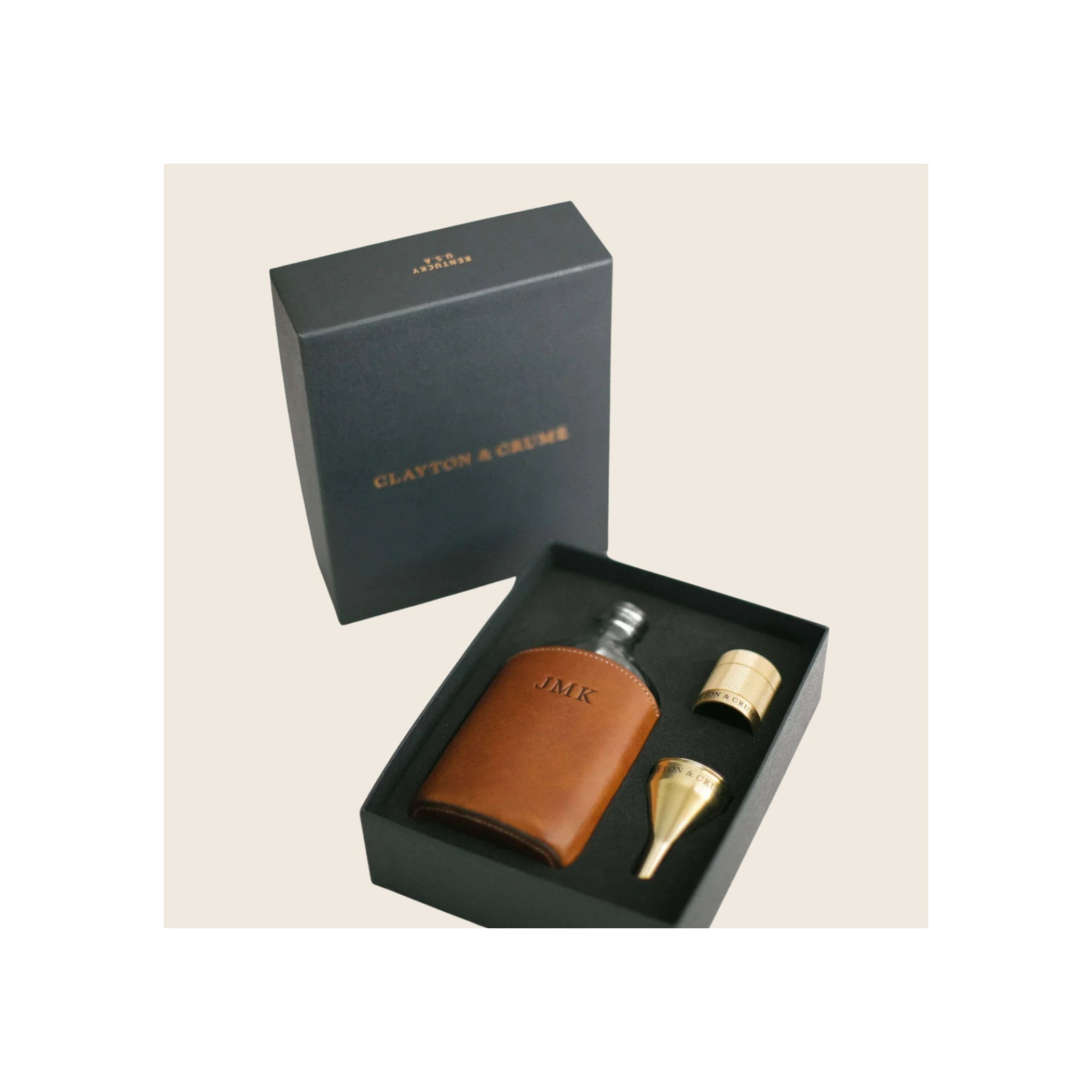 Glass flask in tan leather monogrammed sleeve, with gold funnel and cup, inside open dark gift box