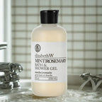 Shower gel bottle, cream frosted plastic with black flip cap, upright on wet bathroom sink surface