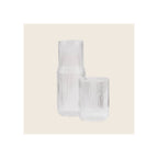 Ribbed clear glass carafe and matching tumbler, vertical ribbed texture, upright front-facing orientation