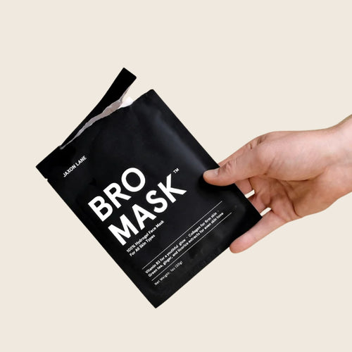Bro Mask black hydrogel face mask packet held in a man's hand, front-facing upright orientation