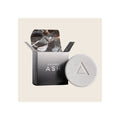 Round white speckled volcanic ash soap bar with triangle emboss beside open black branded box