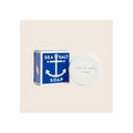 Sea salt soap round white bar beside blue anchor-motif product box, upright on neutral background