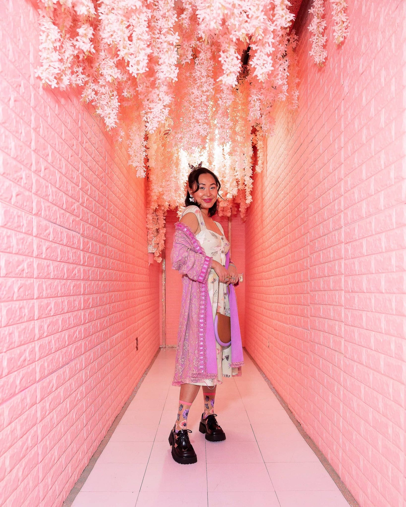 Sheer crew socks with sunflower and butterfly print worn with black chunky shoes in pink floral corridor