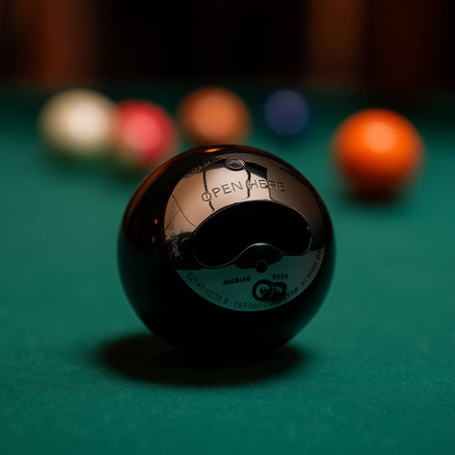 Black 8-ball bottle opener, glossy spherical shape, on green pool table felt