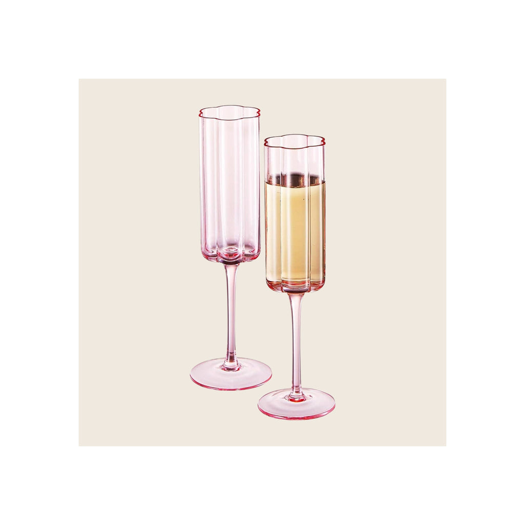 Champagne flutes set of two pink tinted glass with scalloped rims one filled with sparkling wine