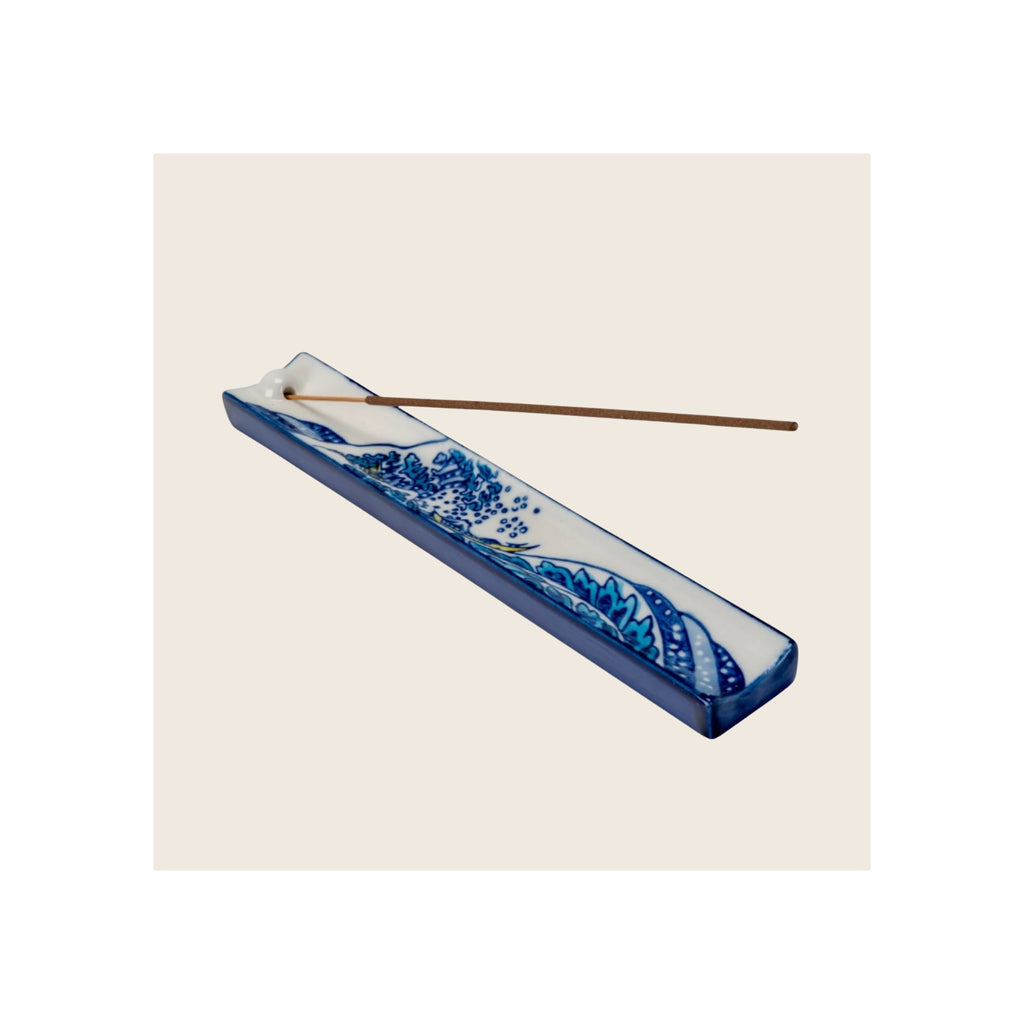 Incense holder, rectangular ceramic, white with blue wave pattern, incense stick resting in holder, diagonal orientation