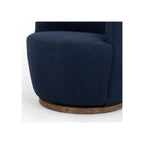 Detail shot of navy bouclé seat base and lower chair body against circular parawood swivel platform