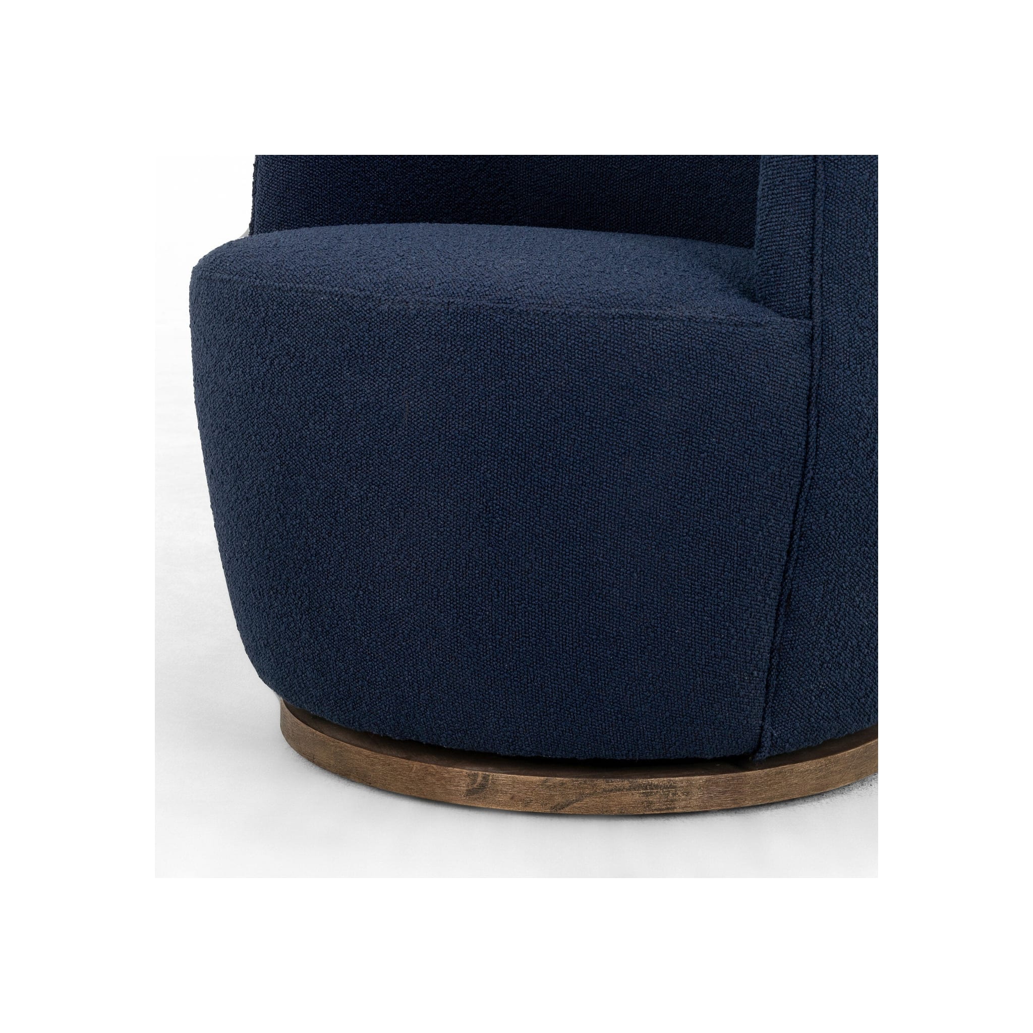 Detail shot of navy bouclé seat base and lower chair body against circular parawood swivel platform