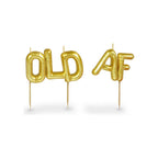 Party candles spelling OLD AF in gold metallic balloon-style letters on wooden picks