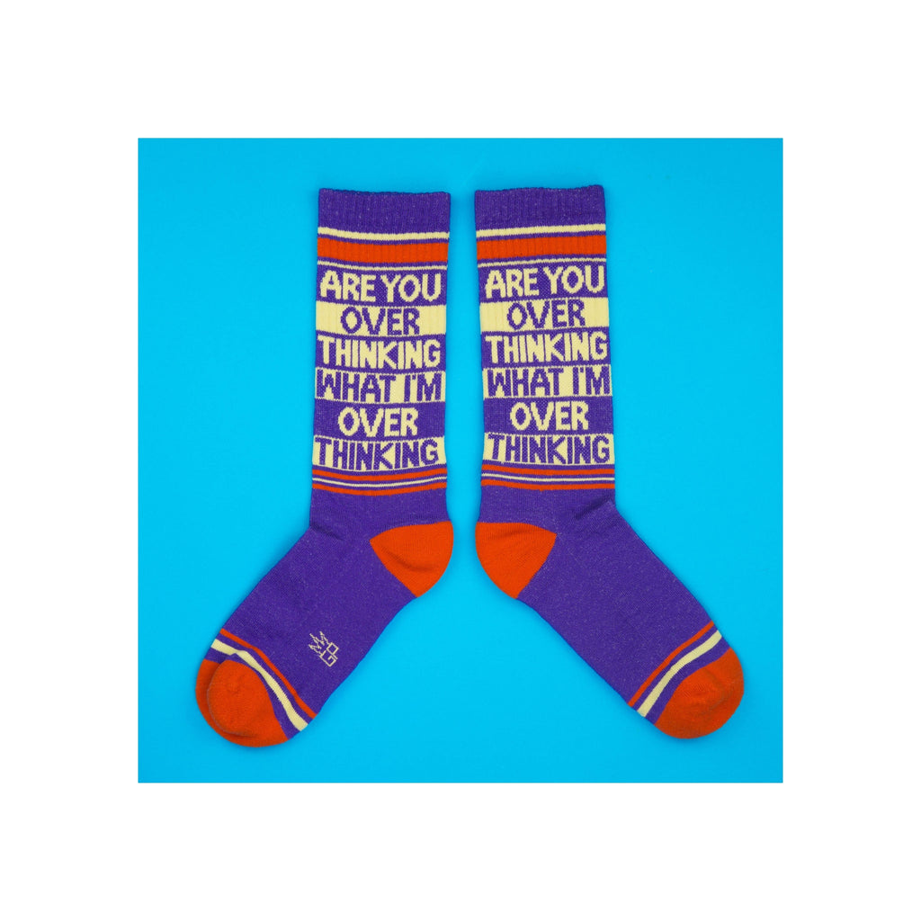 Pair of purple crew socks with orange heels, red stripes, and cream novelty slogan text