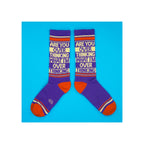 Pair of purple crew socks with orange heels, red stripes, and cream novelty slogan text