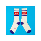 Crew socks, white with purple heel and toe, red stripe panel with white "SLUT" text, flat lay pair