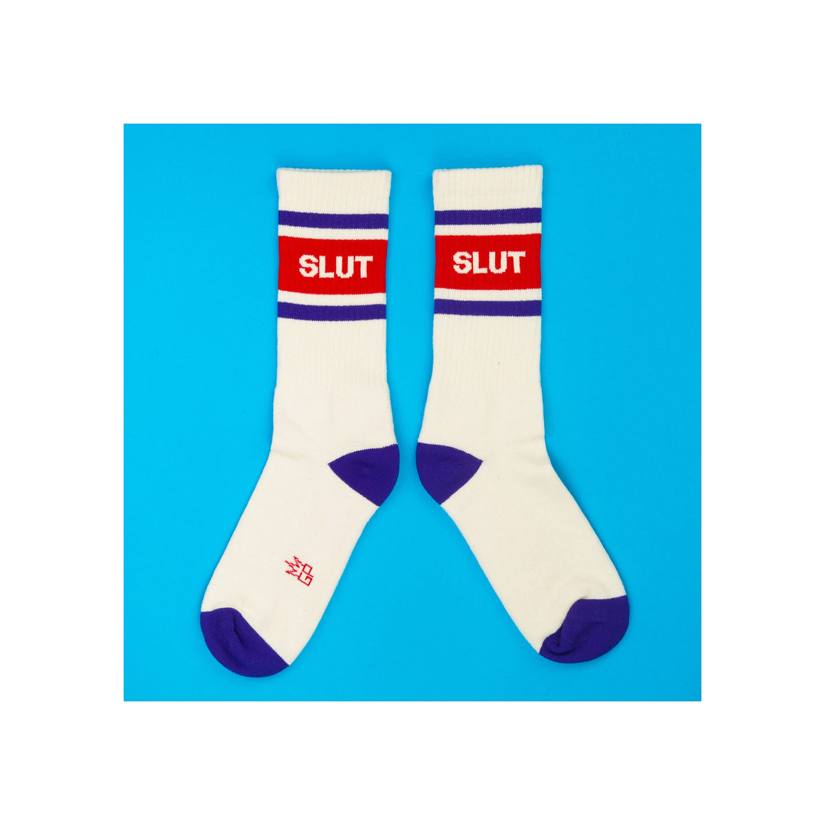 Crew socks, white with purple heel and toe, red stripe panel with white "SLUT" text, flat lay pair