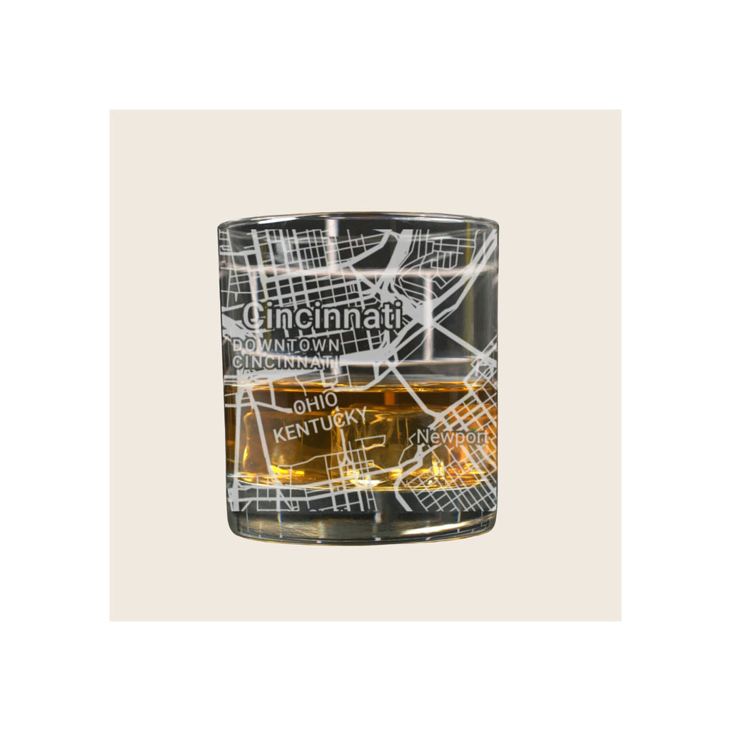 Whiskey glass with engraved Cincinnati street map design, filled with amber liquid, on white background