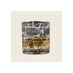 Whiskey glass with engraved Cincinnati street map design, filled with amber liquid, on white background