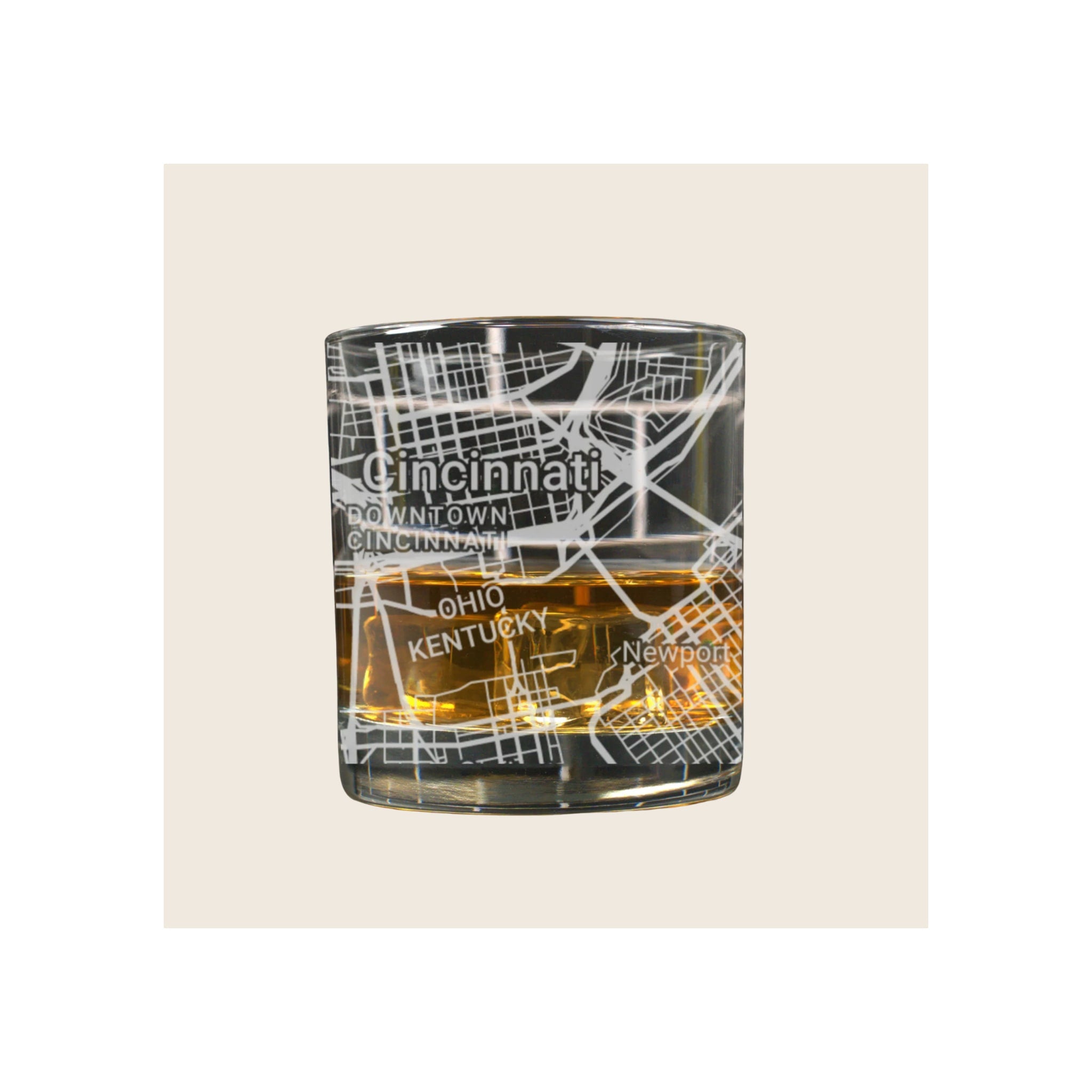 Whiskey glass with engraved Cincinnati street map design, filled with amber liquid, on white background