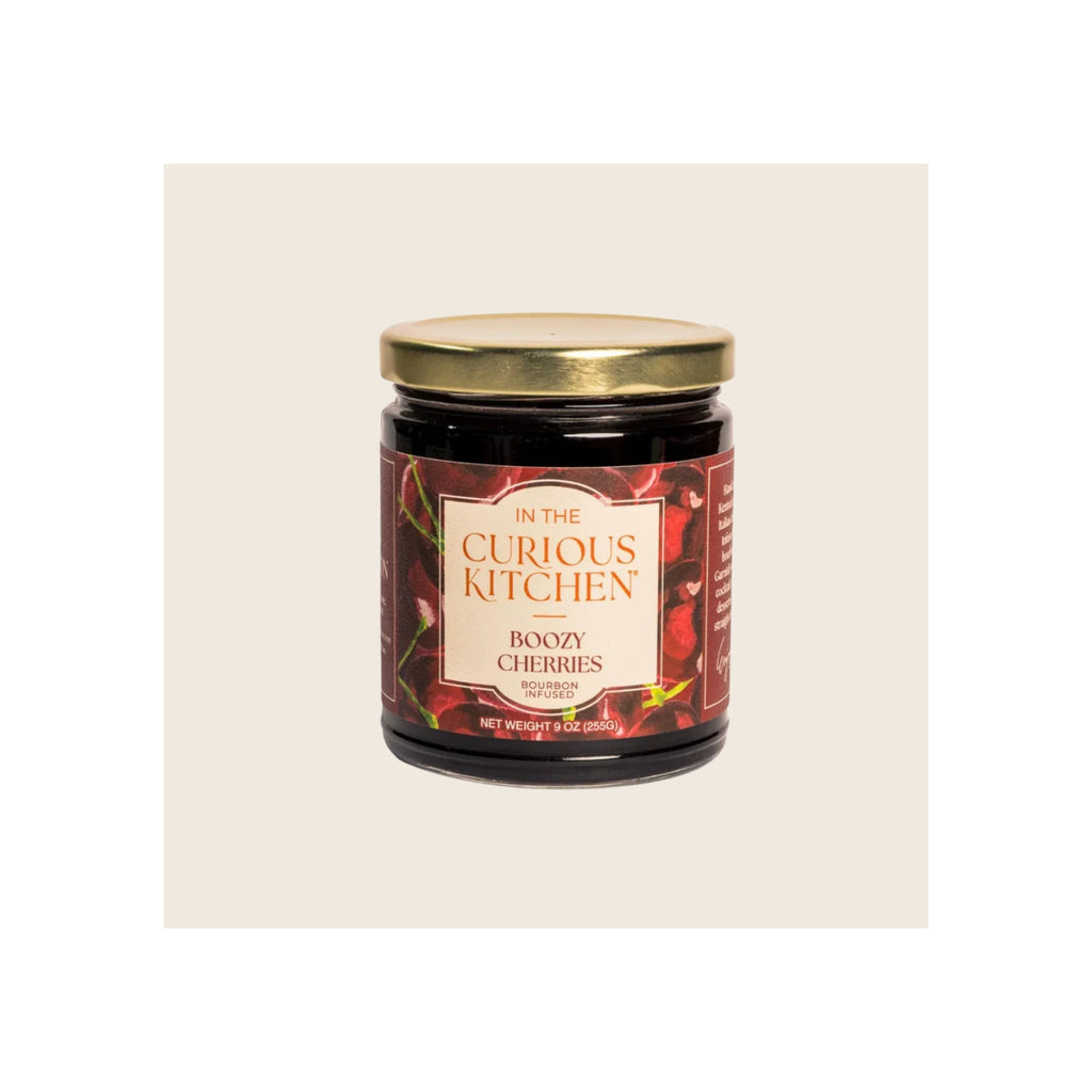 Glass jar of bourbon-infused boozy cherries, gold metal lid, dark red label, upright front view
