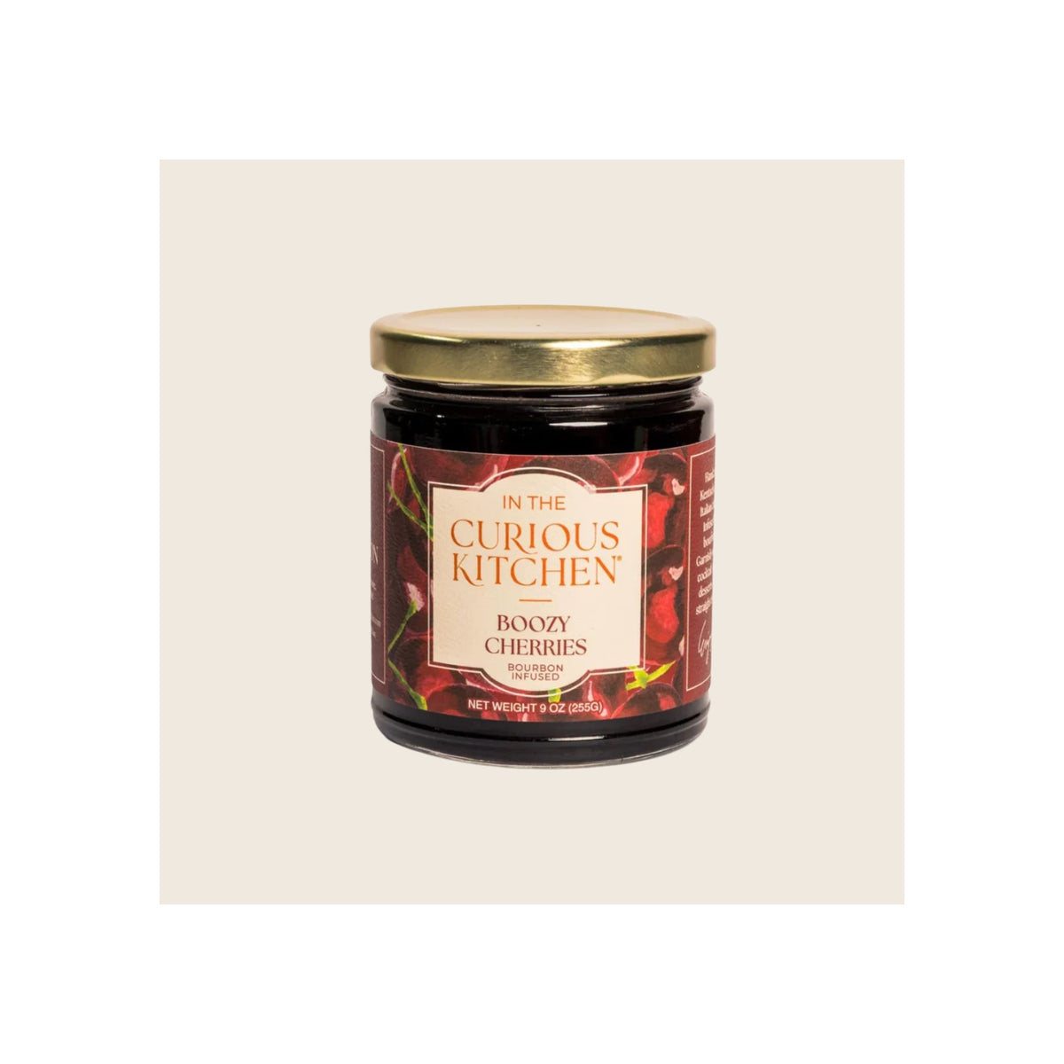 Glass jar of bourbon-infused boozy cherries, gold metal lid, dark red label, upright front view