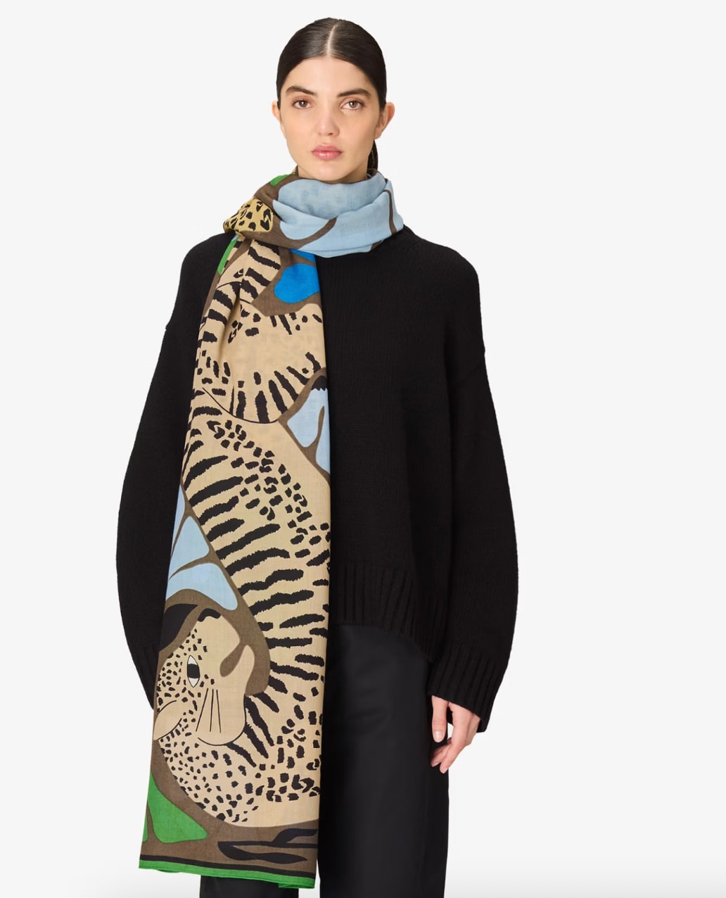 Scarf draped over model's shoulders, khaki and blue leopard-print woven design, front-facing view