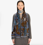 Scarf draped around model's neck, brown and blue floral jungle print with striped border