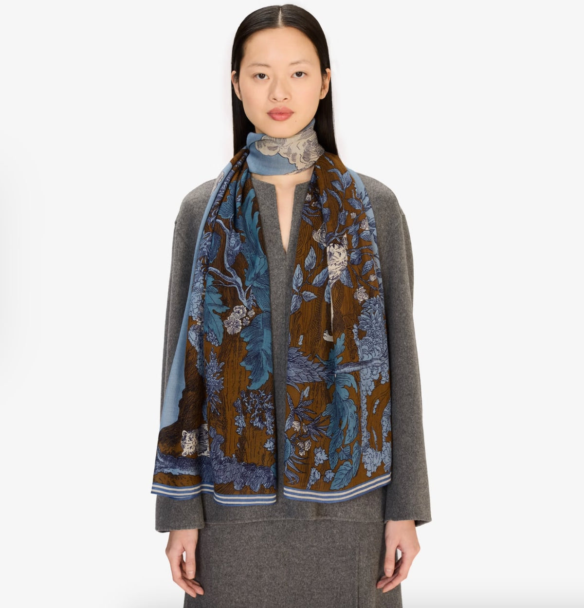 Scarf draped around model's neck, brown and blue floral jungle print with striped border