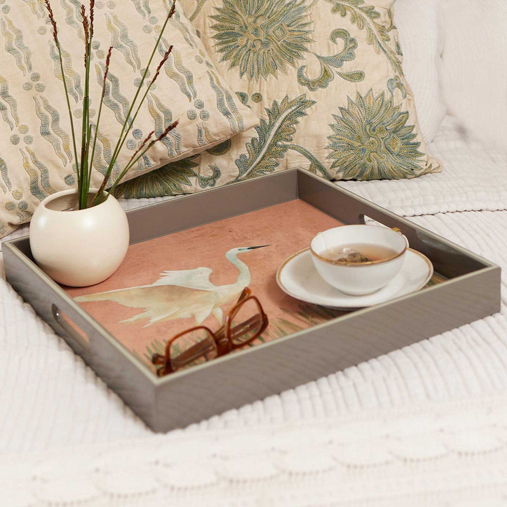 Egret square lacquer serving tray, grey frame with pink egret-print base, styled on white bed
