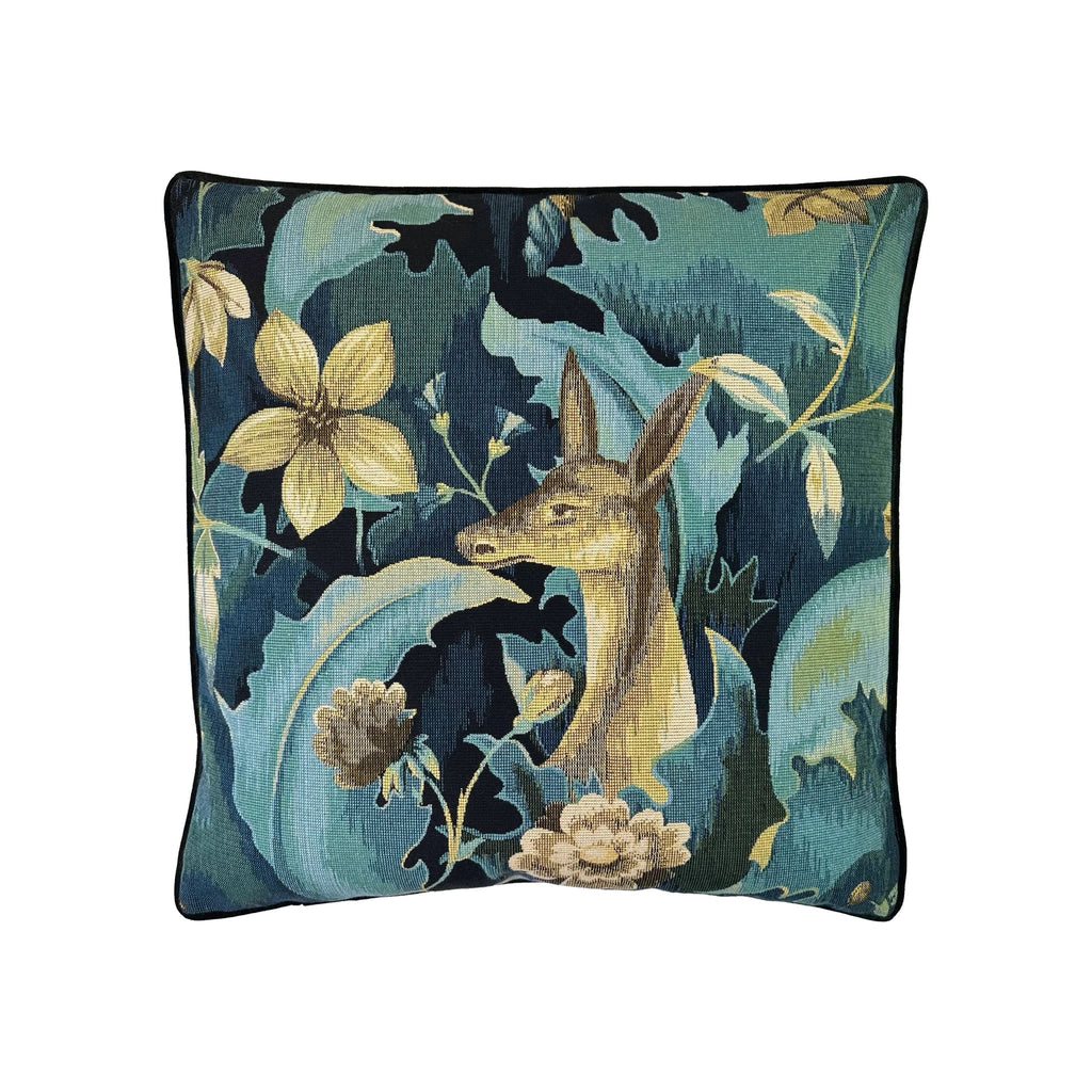 Cushion with teal tapestry-weave print featuring deer, florals, and foliage, black piped border