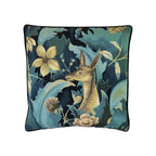Cushion with teal tapestry-weave print featuring deer, florals, and foliage, black piped border