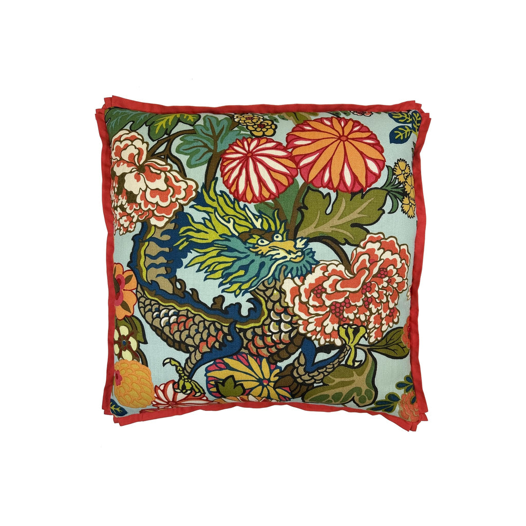Cushion with aquamarine ground, dragon and floral chinoiserie print, red flanged border, front-facing flat lay