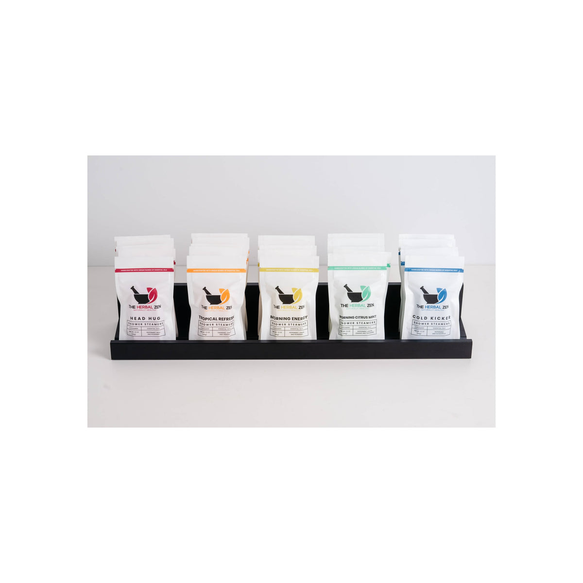 Five Herbal Zen shower steamer pouches in white packaging displayed upright in black tray, front-facing