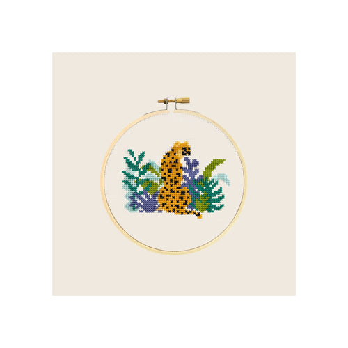 Cross stitch embroidery hoop, completed cheetah amid tropical foliage, natural wood frame, front-facing